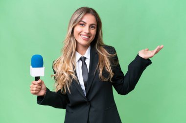 Genç, güzel Uruguaylı televizyon sunucusu izole edilmiş arka planda davet edilmek için ellerini yana uzatıyor.