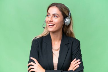 Tele pazarlamacı güzel Uruguaylı kadın izole bir arka planda çalışan mutlu ve gülümseyen bir kulaklıkla.