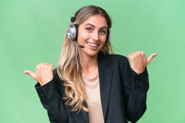 Tele pazarlamacı güzel Uruguaylı kadın izole bir arka planda çalışan, baş parmakları havada ve gülümseyen bir kadın.