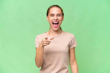 İzole edilmiş geçmişi olan beyaz bir kadın şaşırmış ve ön tarafı işaret ediyor.