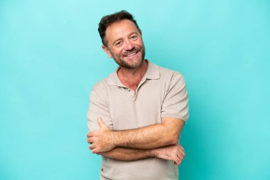 Orta yaşlı beyaz bir adam mavi arka planda izole edilmiş gülüyor.