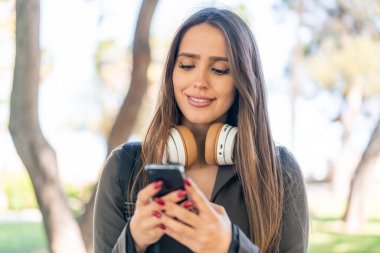 Açık havada cep telefonu kullanan genç bir kadın.