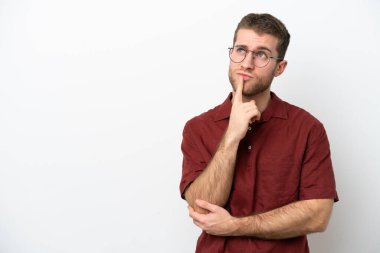 Beyaz arka planda izole edilmiş genç beyaz adam yukarı bakarken şüpheleri var.