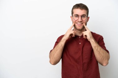 Beyaz arka planda izole edilmiş genç beyaz bir adam mutlu ve hoş bir ifadeyle gülümsüyor.