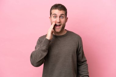 Pembe arka planda mahsur kalmış, şaşırmış ve şok olmuş genç bir beyaz adam.