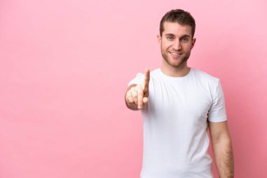 Pembe arka planda izole edilmiş genç beyaz adam parmağını kaldırıyor ve gösteriyor.