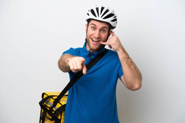 Beyaz arka planda izole edilmiş termal sırt çantalı beyaz bir adam telefon hareketi yapıyor ve ön tarafı işaret ediyor.