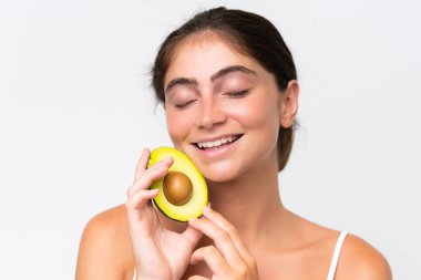 Young Pretty caucasian woman isolated on white background holding an avocado while smiling. Close up portrait