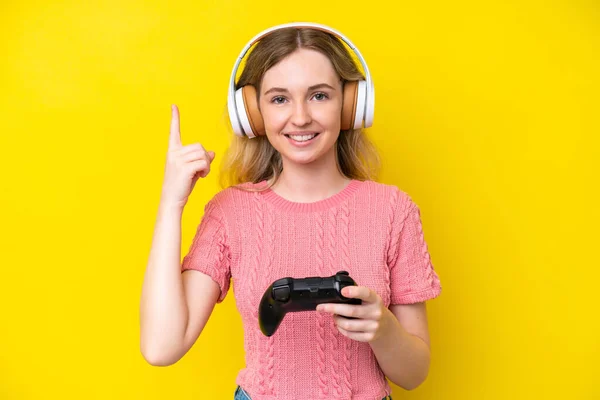Blonde英国小女孩玩一个黄色背景的视频游戏控制器 提出了一个很好的主意 — 图库照片