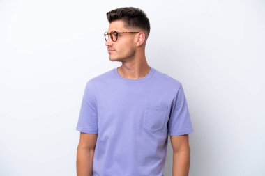 Beyaz arka planda izole edilmiş genç beyaz adam yan tarafa bakıyor.