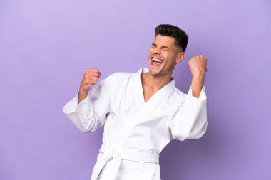 Mor arka planda karate yapan genç beyaz bir adam zaferi kutluyor.
