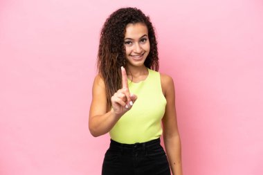 Pembe arka planda izole edilmiş genç İspanyol kadın parmağını kaldırıyor ve gösteriyor.