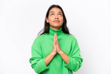 Young Colombian woman isolated on white background keeps palm together. Person asks for something