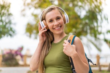 Açık havada müzik dinleyen genç sarışın kadın.
