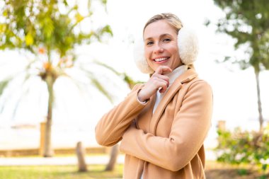 Açık havada kışın kuklalar takan genç sarışın kadın gülümsüyor.