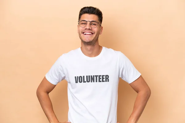Young Volunteer Caucasian Man Isolated Beige Background Posing Arms Hip — Stock Photo, Image