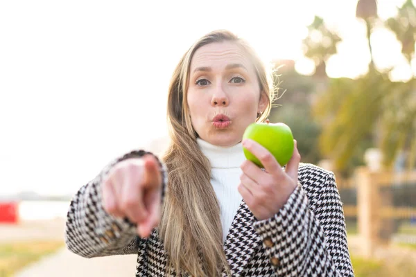 若いですブロンド女性とともにリンゴで屋外で驚きと指摘フロント — ストック写真