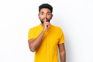 Beyaz arka planda izole edilmiş genç Brezilyalı bir adam sessizlik işareti gösteriyor. Parmağını ağzına sokuyor.