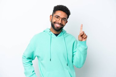 Genç Brezilyalı bir adam beyaz arka planda izole edilmiş ve en iyinin işareti olarak parmağını kaldırıyor.