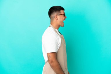 Restoran garsonu mavi arka planda gülüyor.