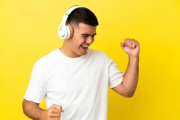 Νεαρός Όμορφος Άντρας Πάνω Από Απομονωμένο Κίτρινο Φόντο Ακούγοντας Μουσική — Φωτογραφία Αρχείου
