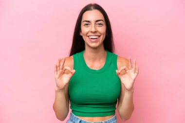 Pembe arka planda izole edilmiş beyaz bir kadın iki eliyle tamam işareti gösteriyor.