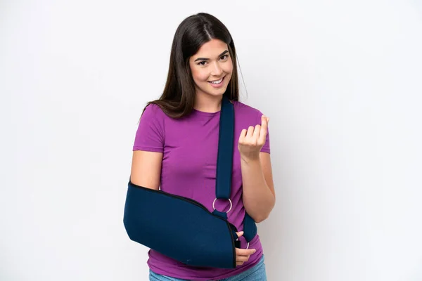 stock image Young Brazilian woman with broken arm and wearing a sling isolated on white background making money gesture