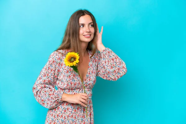 Young Caucasian Woman Holding Sunflower Isolated Blue Background Listening Something — Stock Photo, Image