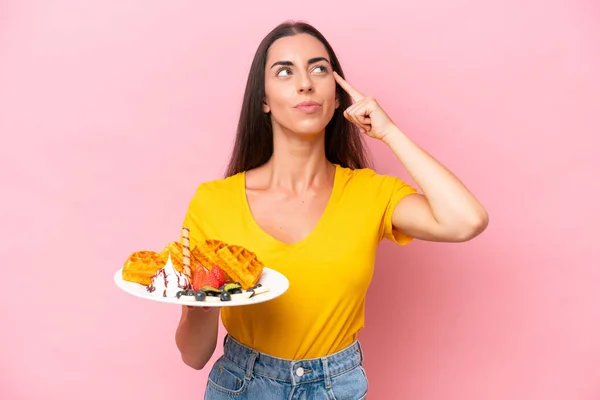 Young Caucasian Woman Holding Waffles Isolated Pink Background Having Doubts — стоковое фото