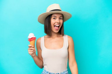 Young caucasian woman holding an ice cream isolated on blue background with surprise facial expression