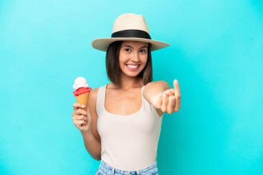 Elinde dondurma tutan beyaz bir kadın. Mavi arka planda izole edilmiş. Gelen hareketi yapıyor.