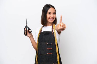 Beyaz arka planda izole edilmiş genç terzi kadın parmağını kaldırıyor ve gösteriyor.