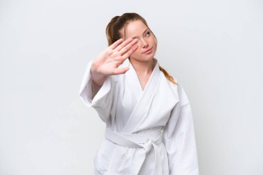 Beyaz arka planda karate yapan beyaz bir kız dur hareketi yapıyor ve hayal kırıklığına uğruyor.