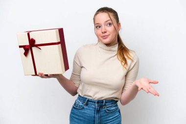 Beyaz arka planda izole edilmiş bir hediye tutan beyaz bir kadın omuzlarını kaldırırken şüphe uyandıran hareketler yapıyor.