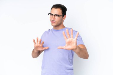 Beyaz arka planda izole edilmiş genç beyaz bir adam sinirleri gergin ve ellerini öne uzatıyor.