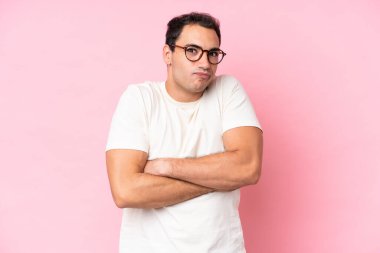 Young caucasian man isolated on pink background making doubts gesture while lifting the shoulders