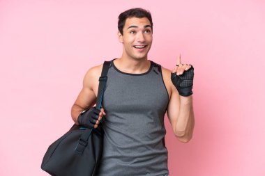 Spor çantalı genç beyaz adam pembe arka planda izole edilmiş ve şaşırmış.