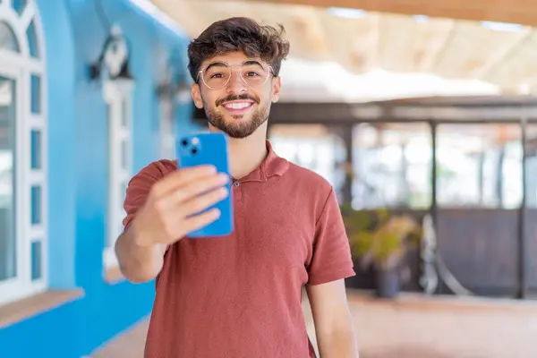 Mladý Arabský Pohledný Muž Používající Mobilní Telefon Venku Veselým Výrazem — Stock fotografie