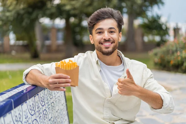 Jonge Arabische Knappe Man Houdt Gebakken Chips Buiten Met Duimen — Stockfoto