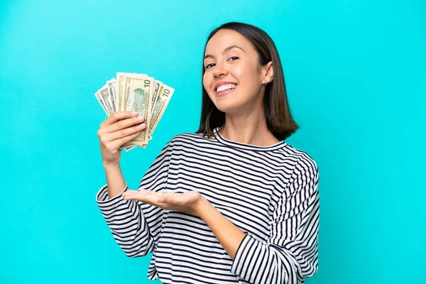 stock image Young caucasian woman taking a lot of money isolated on blue background extending hands to the side for inviting to come