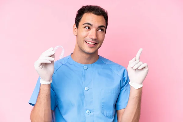 Οδοντίατρος Καυκάσιος Που Κρατάει Αόρατα Σιδεράκια Απομονωμένα Ροζ Φόντο Δείχνοντας — Φωτογραφία Αρχείου
