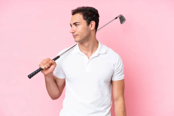 年轻的高尔夫球手男子孤立在粉红的背景下 向侧面看去 — 图库照片