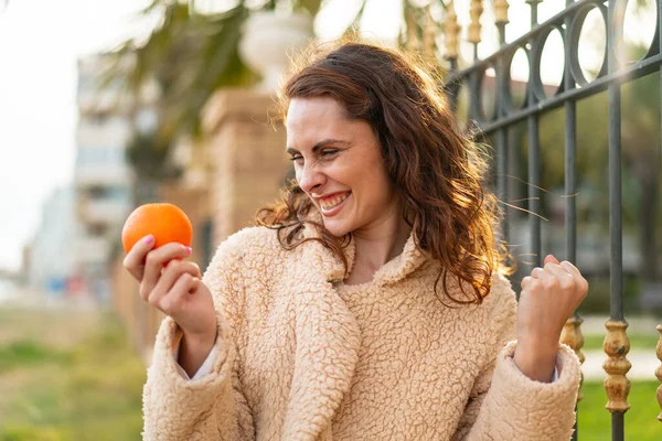 Dışarıda Elinde Portakal Tutan Beyaz Bir Kadın Zaferi Kutluyor — Stok fotoğraf