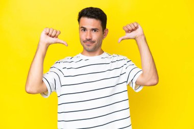 Genç yakışıklı, soyutlanmış sarı arka plan gururlu ve kendini beğenmiş.