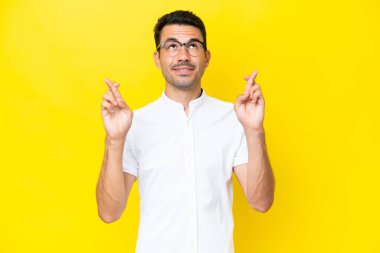 Genç yakışıklı, izole edilmiş sarı arka planda, şans diliyor ve en iyisini diliyor.