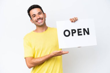 Soyutlanmış beyaz arka planda genç yakışıklı bir adam elinde mutlu bir ifadeyle barış sembolü taşıyan bir pankart tutuyor.