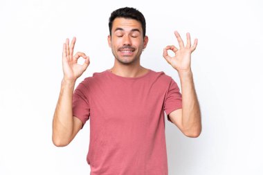 Zen pozisyonunda soyutlanmış beyaz bir geçmişi olan yakışıklı bir genç.