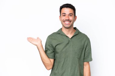 İzole edilmiş beyaz arka plan üzerinde genç yakışıklı bir adam bir ilan vermek için avucunun içinde hayali bir mekan tutuyor.