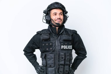 Beyaz arka planda, kolları kalçasında poz veren ve gülümseyen beyaz bir SWAT elemanı var.