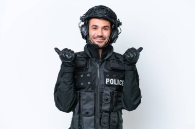 Beyaz arka planda izole genç beyaz SWAT adamı baş parmaklar yukarı jest ve gülümseme ile